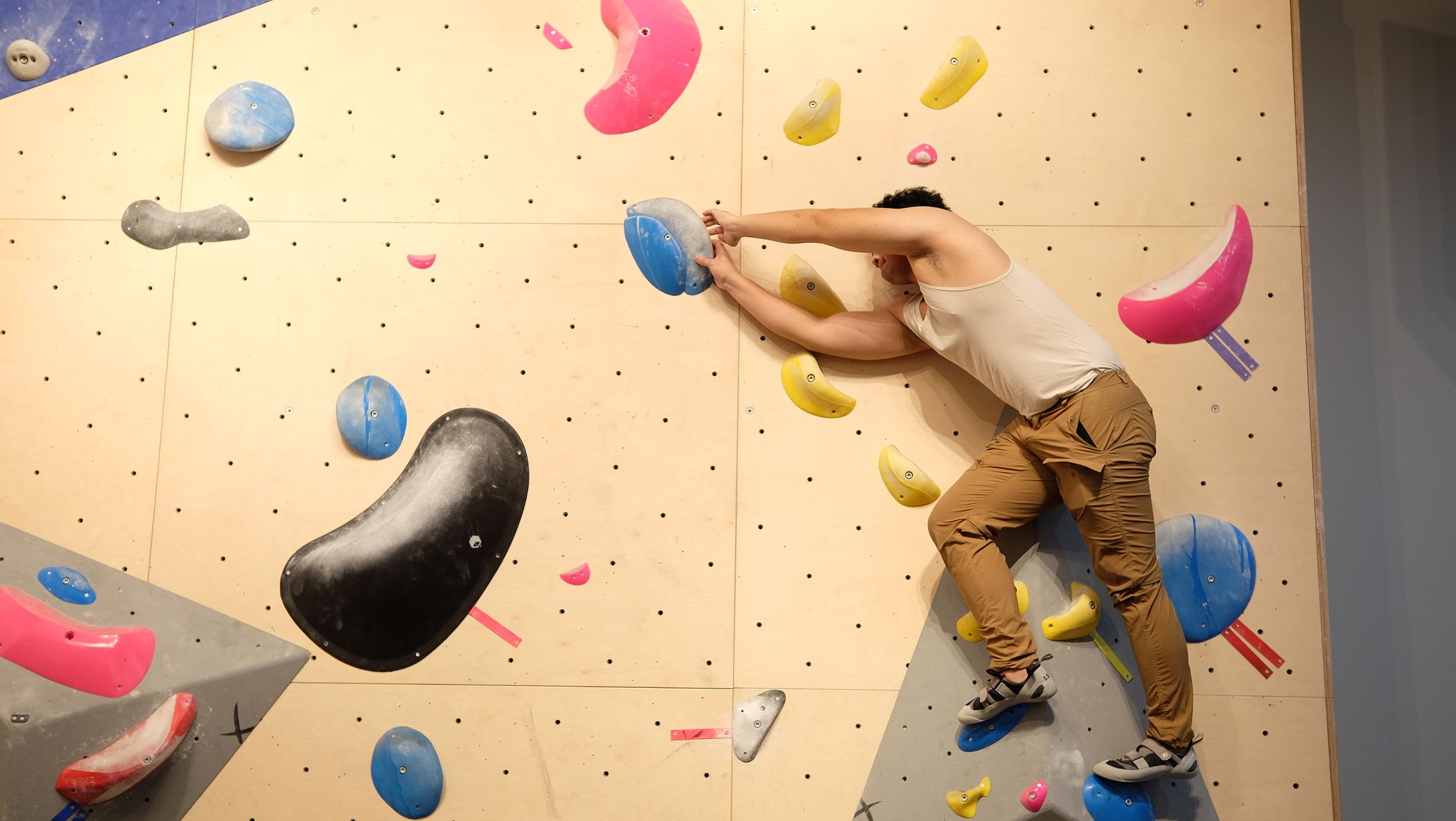Wspinacz na kolorowej ścianie boulderingowej